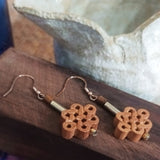 Close-up on two peach wood crafted mini chinese knots 925 silver ear wire drop earrings are refillable fragrance diffuser

