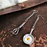 Two endearing 925 silver ear wire dangle earrings elongated by delicate metal chain, features well-made miniature frying egg saucepan and egg whisk