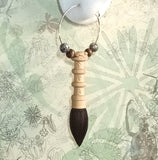 Close-up of copper hoop earrings features a box wood ancient chinese calligraphy brush with sandal wood tip, display on a white ear model
