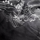 Close up of light weight black silk wool scarf has embroidered a big white line art landscape pattern showing an ancient Chinese village with power towers on the hills