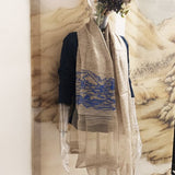 Sheer and soft hemp color silk wool shawl embroidered an artistic blue line art landscape picture of a landscape accommodate an ancient village where chinese huts, animal and power towers are found.