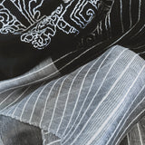 Close-up of the hem finishing and texture of a black silk wool scarf that hand embroidered a big ancient oriental bucket arch in white stitches. 
