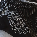 Close up of black light weight silk wool scarf features white pin-stripes and a big hand embroidery of white line art of traditional chinese bucket arch and ornaments. 