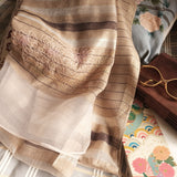 Lightweight sheer beige scarf with brown fine stripes and organza at the bottom is hand embroidered a big floral line art pattern in multi color threads.