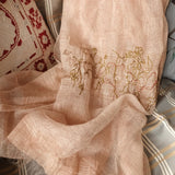 A light coral color silk linen artistic scarf is in rich of linear texture, and has a hand embroidery depicting a surreal scenery including a small temple, house, and flying UFO.