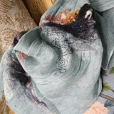 Baby blue 2 tone weave linen shawl, hand-stitched swirl shape pattern next to red-black-white color hand felted wool forms a surreal landscape .