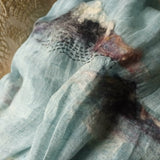 Close up of a baby blue pure linen scarf featured by hand-felted irregular pattern and hand stitched swirl-like pattern.