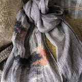 A black and white two-tone weave linen scarf with hand embroidery and hand wool felting depicting a surreal landscape pattern