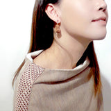 925 sterling silver dangle earring is featured by a mini size peach wood well crafted baby shoe, wear by a chinese young lady in beige fashion knit top