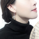 925 sterling silver Star-of-David dangle earring highlighted by blue glass and wood beads, wear by a chinese young lady in black jumper