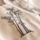 Close-up the embroidery pattern of a cat resting under a tree with white blossom, on a soft and light weight super fine cashmere scarf 